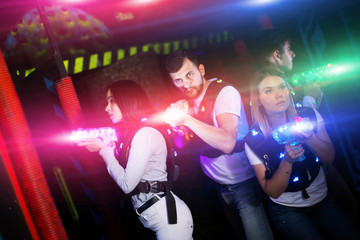 Young people in bright beams during laser tag game