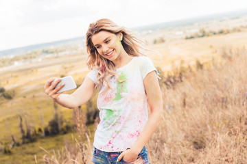 Fototapeta na wymiar attractive woman in t-shirt smiling and taking selfie outside