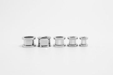 Steel ear stretchers, ear tunnels on white background. Varied sizes, side by side.
