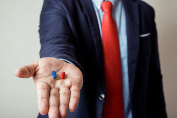 businessman giving blue and red pill in hand , select the way or plan A or B