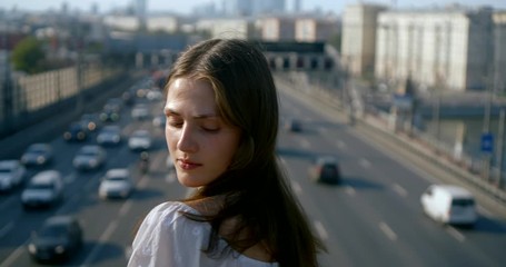 lady poses on trestle over blurry cars driving along road