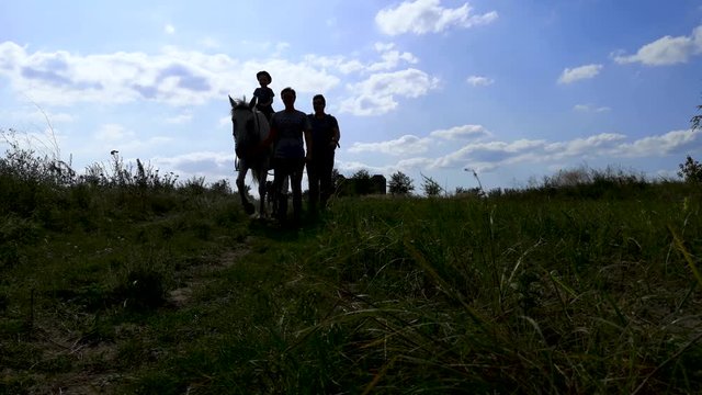 Video of people in the shadow walking on a horse. The concept of family camping, horseback riding and hippotherapy. Dark silhouettes for a detailed sense of the concept video.