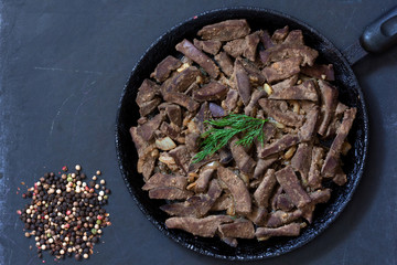 Cooked liver on frying pan on the black background