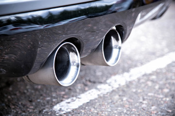 Dual exhaust pipes of a sports car. Silver color with soot from smoke. Close up