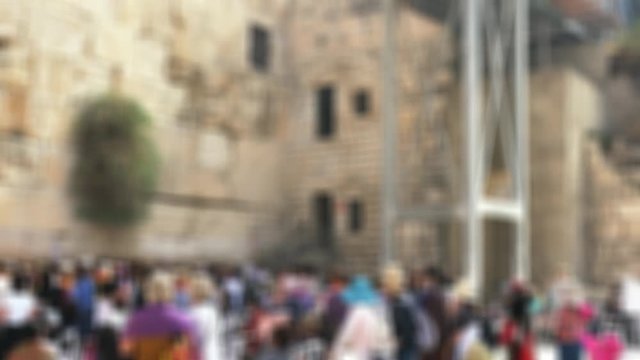 Women praying below at the Western Wall in the morning. Female part of the Wailing Wall. Blurred view