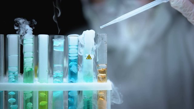 Lab worker pouring liquid in test tube with ionic radiation symbol, research