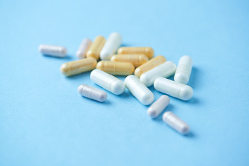 Vitamins and supplements on bright paper background. Concept for a healthy dietary supplementation. Close up. Copy space. 