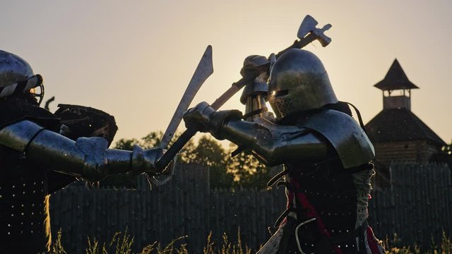 Battle of two knights in armor at sunset.