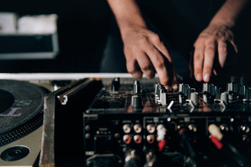 close up of a Dj moving knobs in a mixer in a dark atmosphere