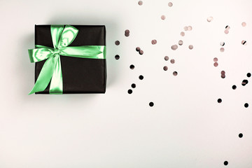 Black gift box with mint bow on white background with glitter. Holiday concept.