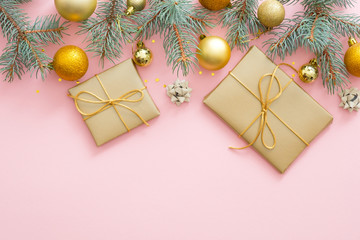 Christmas composition. Fir tree branches, gift boxes, golden balls, confetti, decorations on pastel pink background. Flat lay, top view, copy space. Christmas, winter, New Year concept.