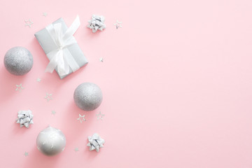 Obraz premium Christmas silver decorations on pastel pink background with copy space. Flat lay, top view. Christmas greeting card mockup, social media banner template. Glamour fashion Christmas celebration concept