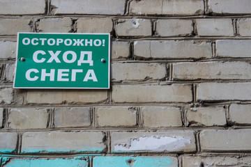 Danger of falling ice and snow: sign. Warning sign in Russian " Cautiously falling snow from the roof"
