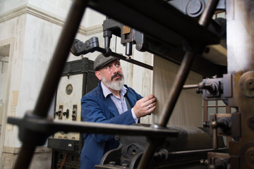 Fototapeta na wymiar Mechanic working on a vintage printing press