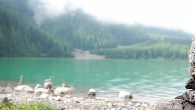 man-made pile (or stack) of stones on beautiful anterselva blue transparent lake in the cloudy sunny afternoon in dolomites alps mountains, bolzano, trentino alto adige, south tyrol, italy, summer 201