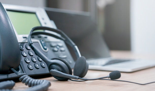 close up soft focus on headset with telephone devices at office desk for customer service support concept