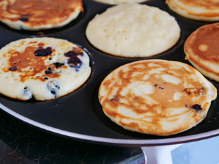 Mini pancakes frying in pancake pan. Silver dollar blueberry pancakes.