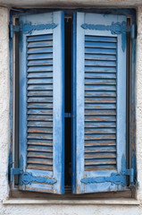 A blue window in the center and a white wall. Traditional greek architecture