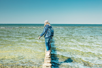 Woman balancing on .piles at baltic sea