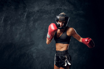 Portrait of attractive boxer in protective helmet and gloves ready to fight.
