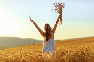 Beautiful young woman in wheat field at sunset outdoor .