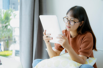 Teen girl using tablet and relaxing at the chair in the co-working space cafe.