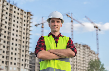civil engineer in white helmets and a yellow vest on the background of the house under construction.
