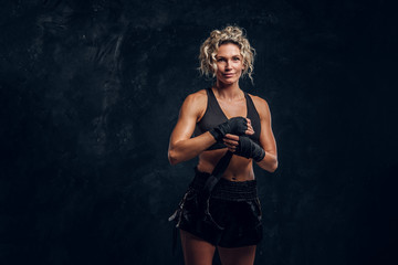 Fototapeta na wymiar Experienced female boxer is posing for photographer while wearing protective bandages.