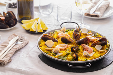 Spanish Seafood Paella with  prawns, clams, mussels on saffron rice and vegetables served in  traditional frying pan  on the restaurant table.