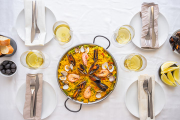 Table setting for friends meeting. Spanish paella for food friends. Top view lifestyle background.