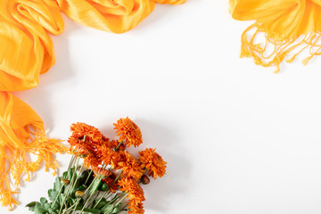 Autumn flowers composition. Orange flowers, scarf on white background. Fall concept. Autumn background. Flat lay, top view, copy space