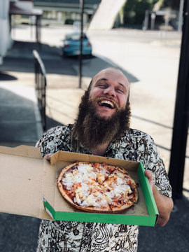 Man with big smile holding up pizza
