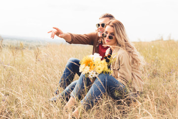 attractive woman with bouquet and handsome man pointing with finger