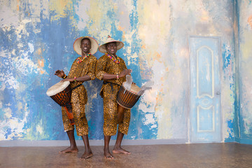 A group of people in traditional african costumes playing jembe drums