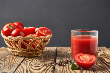 One full glasses of fresh tomato juice lies on old rustic wooden table