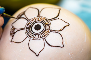 Drawing process of henna mehndi ornament on womans head