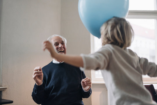 Happy grandfather and grandson playing with balloons at home
