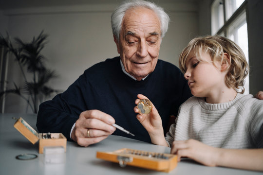 Watchmaker and his grandson examining watch together