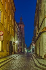 Nocny widok na starą wąską uliczkę w Warszawie, warszawskie kościoły starego miasta, ulica oświetlona latarniami © Jarek Witkowski