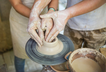 training in pottery. master teaches a girl to make a product from clay