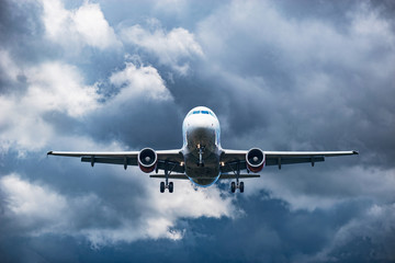 Landing of the plane on the cloudy sky background.