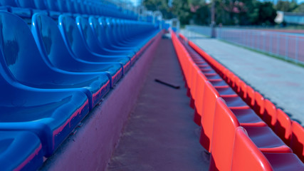 Obraz premium Bleachers in a sports stadium. Red and blue seats in a large street stadium.