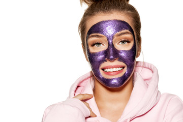 Portrait of beautiful girl wearing facial wetting mask and enjoying treatment. Wellness and beauty concept. Pretty young model in comfy homewear on white background