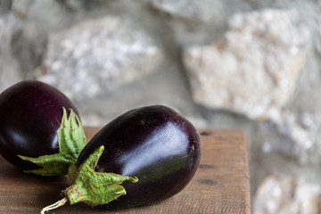 Top view of organic eggplants on wooden table and stone wall background
