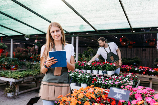 Portrait of a smiling female worker in a garden center using a tablet
