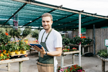 Portrait of a smiling worker in a garden center using a tablet