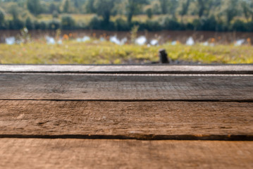 Empty wooden deck table with foliage bokeh background. Ready for product display montage.