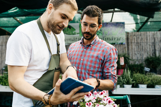 Worker with tablet in a garden center advising customer