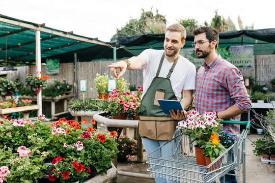 Worker with tablet in a garden center advising customer