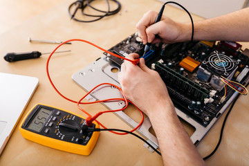 Close-up of technician repairing a desktop computer, checking the continuity of the plates and connectors